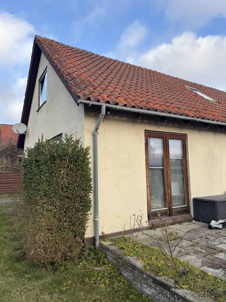 Rødt tegltag med sadeltag på hus med gul facade og ovenlysvindue